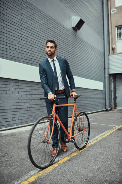 Hes always been conscious about the way he commutes. Shot of a handsome young businessman standing alongside his bike outdoors. - Photo, image
