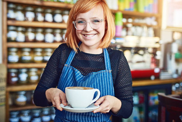 Сочетая ее любовь к кофе с ее предпринимательским духом. Обрезанный снимок женщины, подающей кофе в кафе. - Фото, изображение