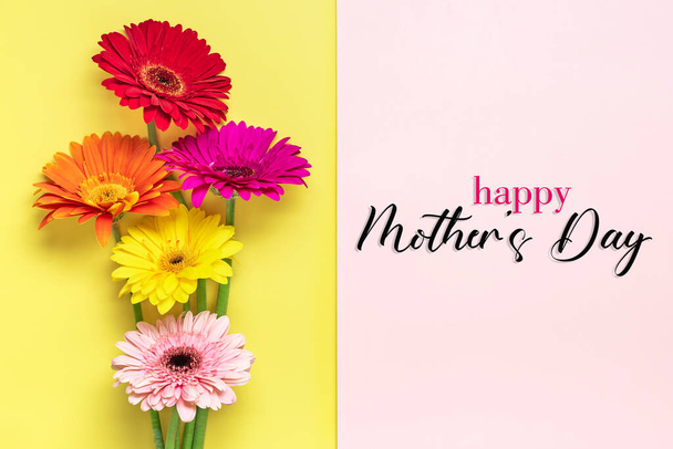 Bouquet of gerberas, text Happy Mother's Day on жовтий, рожевий фон Top view Flat lay Holiday welcome card / - Фото, зображення