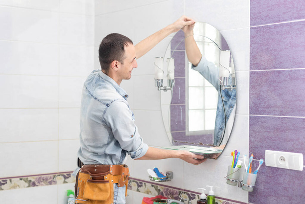 Τεχνίτης εγκαθιστώντας έναν καθρέφτη στο μπάνιο - Φωτογραφία, εικόνα