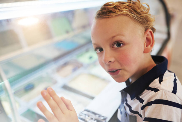 I think Ill just get a scoop of every flavour. Portrait of a young boy looking into a freezer at an ice cream store. - Fotografie, Obrázek