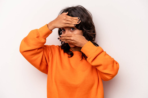 Young hispanic woman isolated on white background blink at the camera through fingers, embarrassed covering face. - Photo, Image
