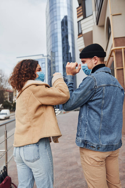 Couple in protective masks greeting each other in the city near business building at quarantine time. Conception of coronavirus. - Valokuva, kuva