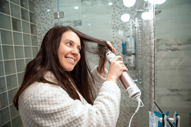 piękna kobieta z suszarką do włosów przed lustrem łazienka - Zdjęcie, obraz