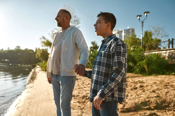 Side view of father and son stand on river coast - 写真・画像