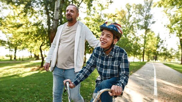 Dad walk and son with cerebral palsy ride bicycle - Fotoğraf, Görsel