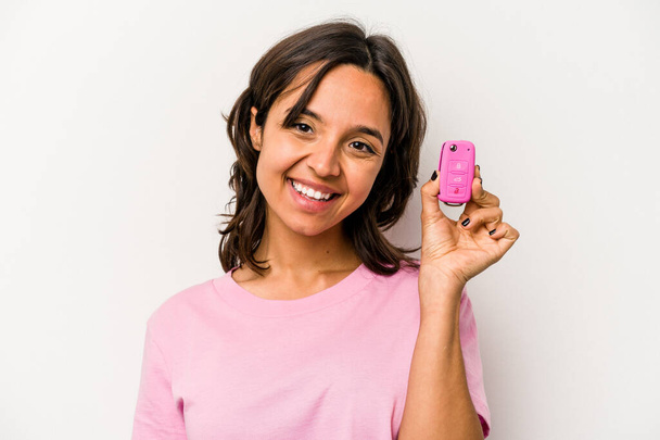 Young hispanic woman holding car keys isolated on white background happy, smiling and cheerful. - 写真・画像