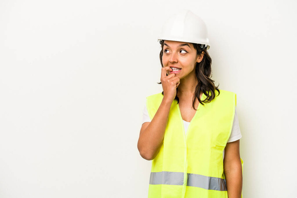 Young laborer hispanic woman isolated on white background relaxed thinking about something looking at a copy space. - Foto, Imagen