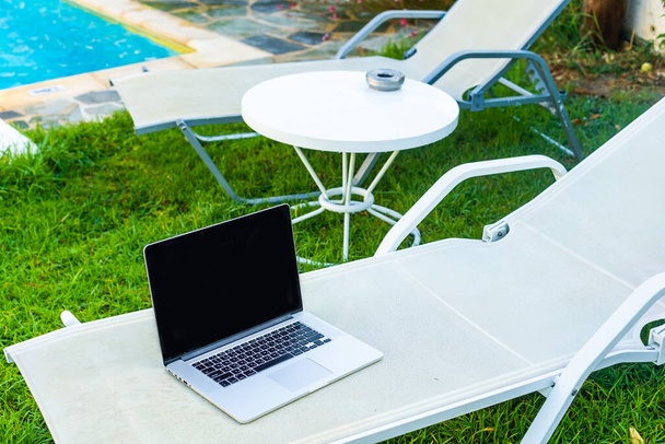 laptop egy napozóágyon a medence mellett - Fotó, kép