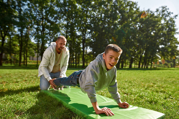 Dad help teenage son with cerebral palsy do plank - 写真・画像