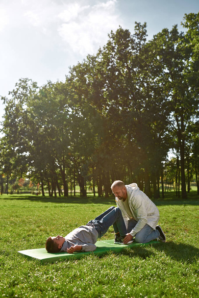 Dad help son do exercise for abdominal muscles - Fotoğraf, Görsel