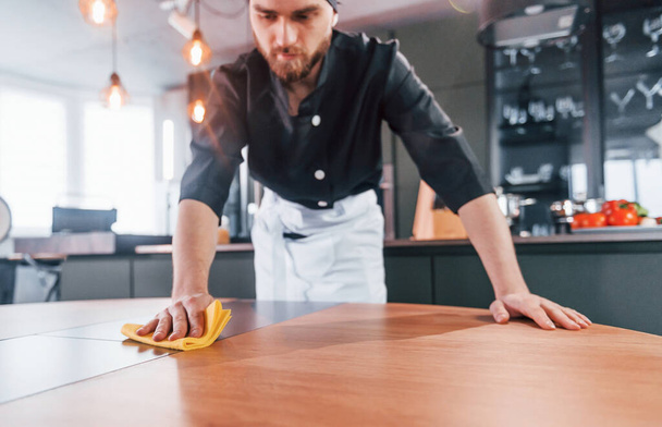 Professional young chef cook in uniform cleaning table on the kitchen. - 写真・画像