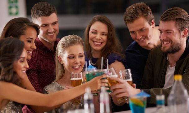 Cheers to Friday night. Shot of a happy group of friends having drinks at a bar together. - Foto, Imagem