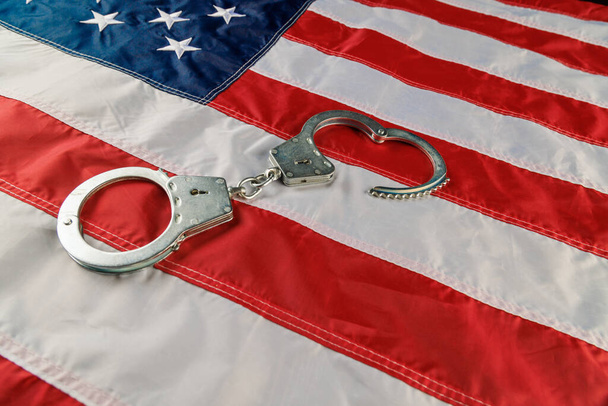 Срібні металеві наручники над прапором США на плоскій поверхні - Фото, зображення