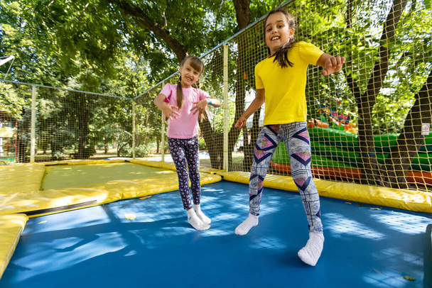 zwei junge aktive Mädchen machen Übungen für die Hocke mit dem Trampolin - Foto, Bild