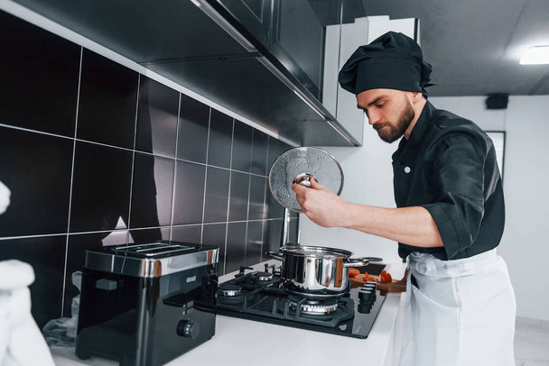 Professional young chef cook in uniform standing on the kitchen. - Valokuva, kuva