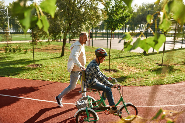 Dad walk, help son with disability ride tricycle - Фото, зображення
