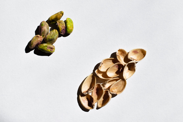 top view of organic and salty pistachios near nutshells on white background - Zdjęcie, obraz