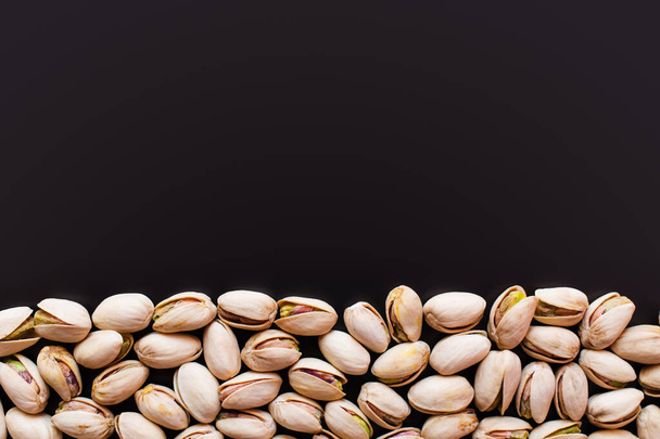 flat lay view of cracked and salty pistachios isolated on black  - Photo, Image