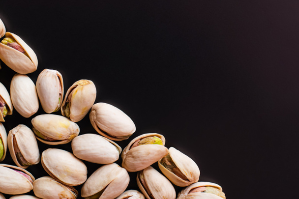 top view of tasty and salty pistachios isolated on black  - Foto, Bild
