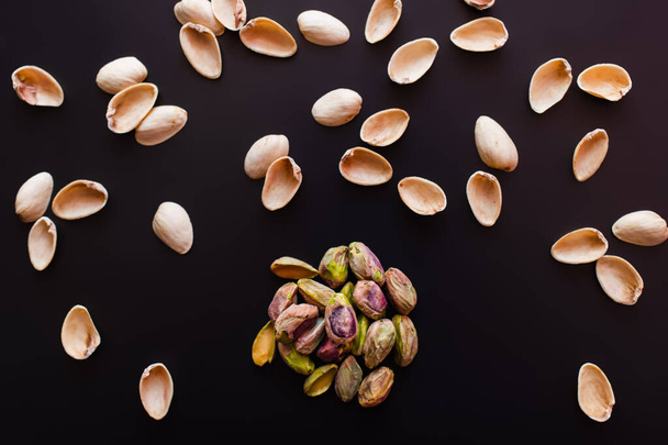 top view of nutshells and salty pistachios isolated on black  - Fotografie, Obrázek
