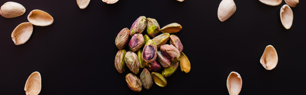 top view of nutshells and salty pistachios isolated on black, banner - Zdjęcie, obraz