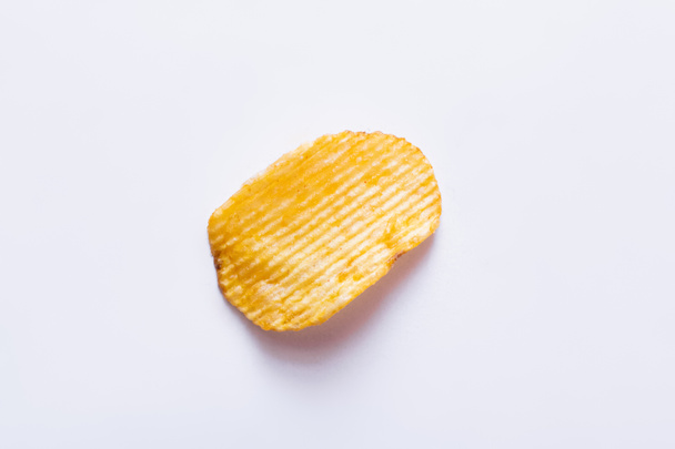 Draufsicht auf einzelne wellige und salzige Kartoffelchips auf weiß - Foto, Bild