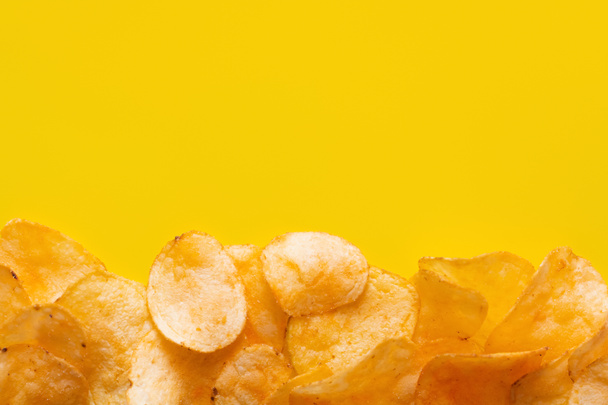 top view of delicious, crunchy and salty potato chips on yellow with copy space - Фото, изображение