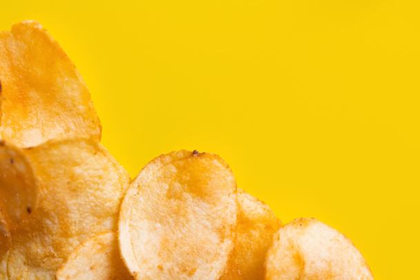top view of delicious, crunchy and salty potato chips on yellow - Foto, imagen