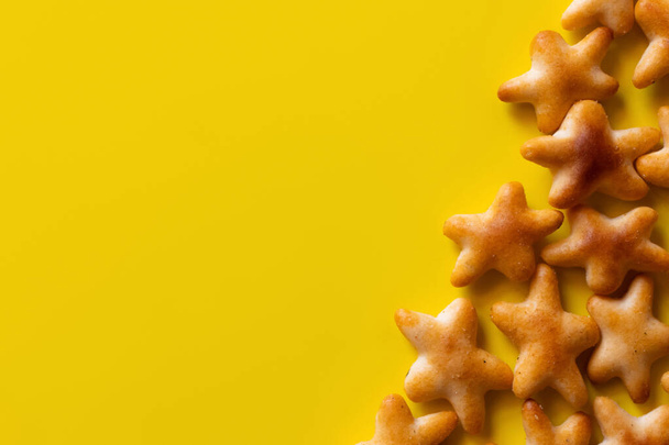 bovenaanzicht van heerlijke koekjes in de vorm van sterren op geel - Foto, afbeelding