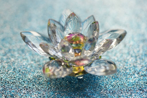 Kristallen lotus op glanzend blauw oppervlak. Paradijsknop symbool - Foto, afbeelding
