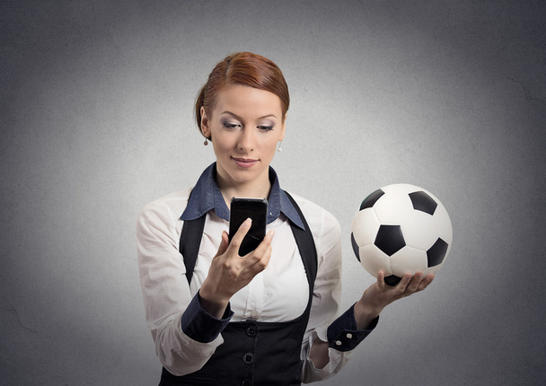 business woman looking on smartphone watching game holding football  - Foto, afbeelding