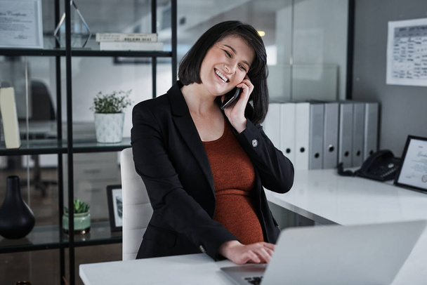 Ich grüße meine Kunden immer positiv. Schnappschuss einer attraktiven schwangeren Geschäftsfrau, die allein im Büro sitzt und Technologie nutzt. - Foto, Bild