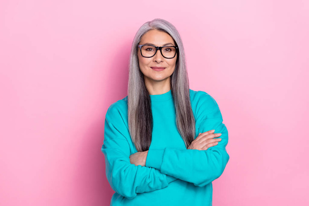 Photo of charming positive retired woman blue sweater spectacles arms crossed isolated pink color background - Fotó, kép