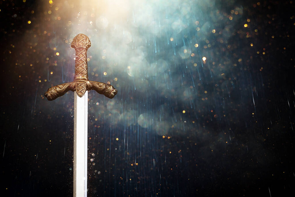 photo of knight sword over dark background. Medieval period concept - 写真・画像