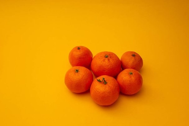 Bright orange tangerines lie on a yellow background - Fotó, kép