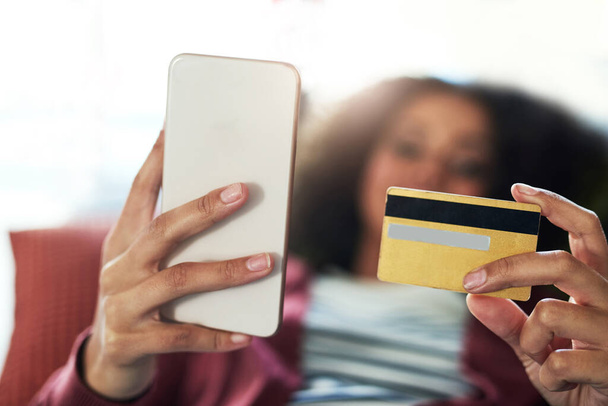 Geen geld, geen probleem. Foto van een jonge vrouw met een mobiele telefoon en creditcard op de bank thuis. - Foto, afbeelding