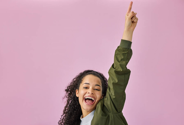 Im having the time of my life. Shot of an attractive young woman standing alone against a pink background in the studio and pointing upwards. - 写真・画像