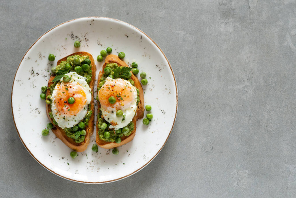 Toasts with green peas and eggs on a concrete background. Homemade healthy pea toast  - Zdjęcie, obraz
