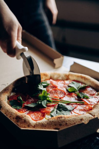 Pyszna i soczysta włoska pizza z kiełbasą jest krojona nożem - Zdjęcie, obraz
