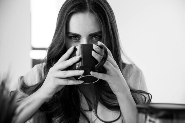 Seductive Girl Drinks Tea and Looks Intriguingly into the Camera. Black and White photo - Φωτογραφία, εικόνα