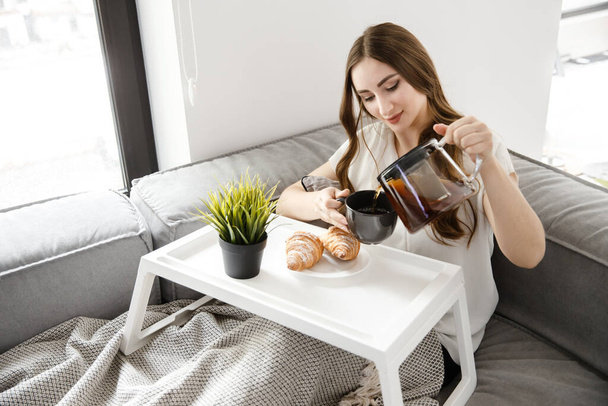 A Young Girl take Breakfast in Bed. French Croissants With Tea on a Tray - Foto, immagini