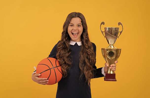 menina adolescente feliz segurar bola de basquete e copo campeão no fundo amarelo, felicidade - Foto, Imagem