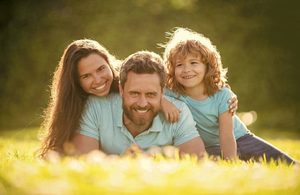счастливая семья мама папа и сын ребенка расслабиться в летнем парке зеленая трава, семейные связи - Фото, изображение