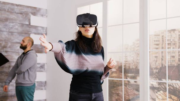 Female architect using virtual reality goggles in empty apartment - Photo, Image