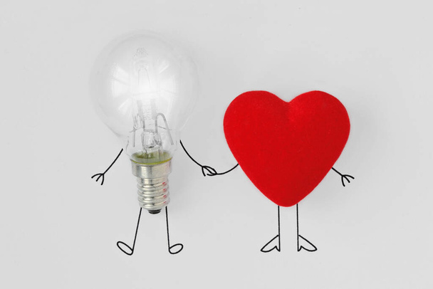Glühbirne und Herz an der Hand - Konzept der Teamarbeit von Gehirn und Herz - Foto, Bild