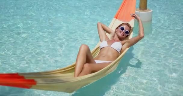 Ευτυχισμένη γυναίκα χαλαρώνει στην αιώρα πάνω από την πισίνα - Πλάνα, βίντεο