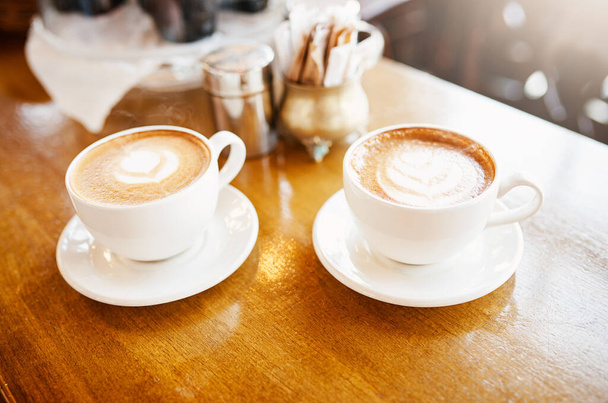 Zijn die voor mij. Hoge hoek opname van twee perfect gepresenteerde kopjes cappuccino in een coffeeshop. - Foto, afbeelding