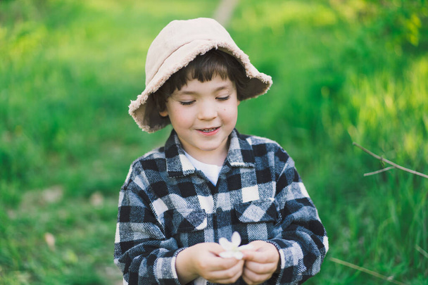 Niño jugando con la rama de un manzano y divirtiéndose. Actividad de primavera para niños curiosos - Foto, imagen