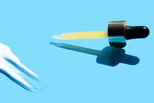 Pipette with dose of fluid hyaluronic acid on blue background. cosmetic concept. flat lay. Place for tex - Foto, Imagem